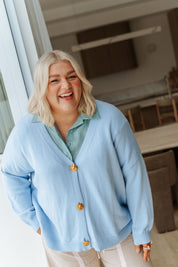 Woman wearing a light blue cardigan with yellow buttons indoors.
