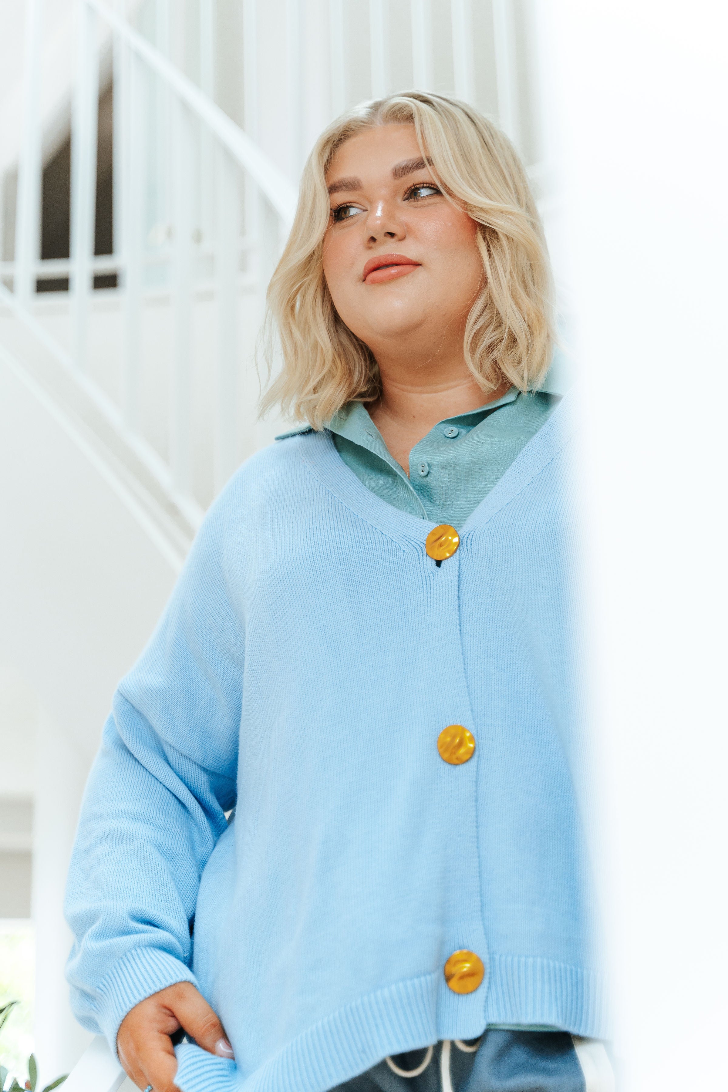 Woman wearing a light blue cardigan with yellow buttons outdoors