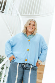 Woman wearing a light blue cardigan with yellow buttons outdoors