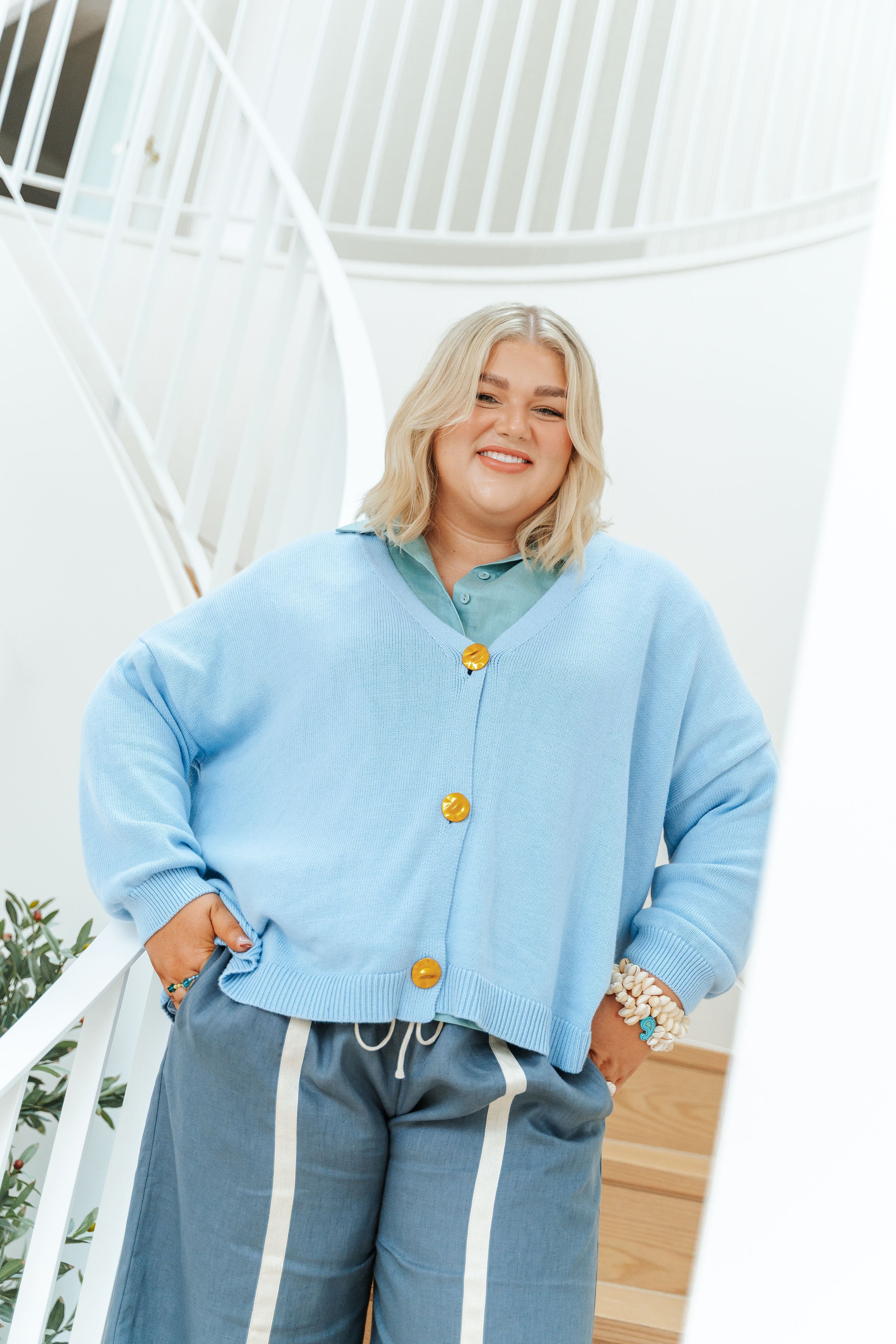 Woman wearing a light blue cardigan with yellow buttons outdoors