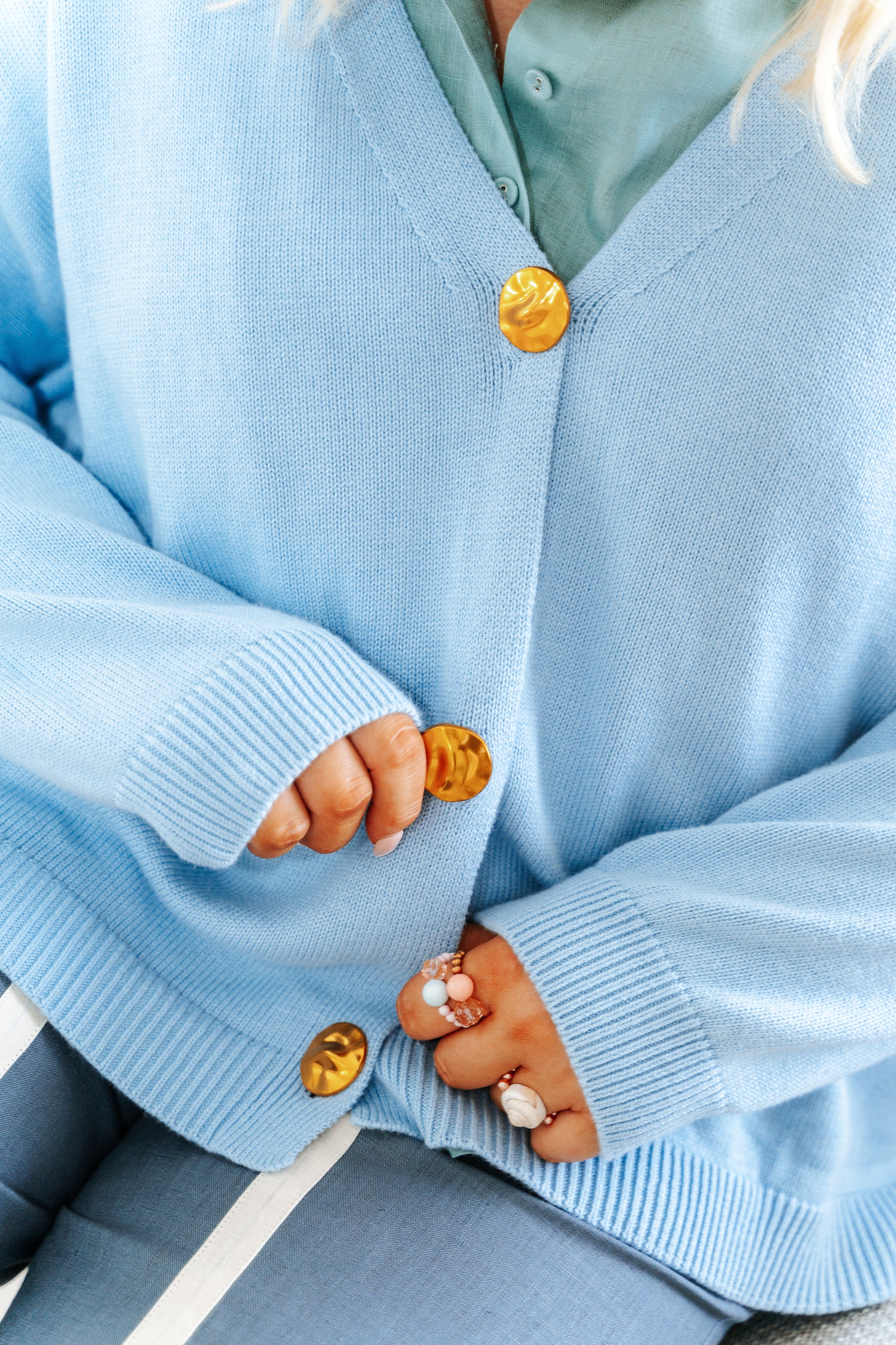 Light blue cardigan with gold buttons worn by a person.