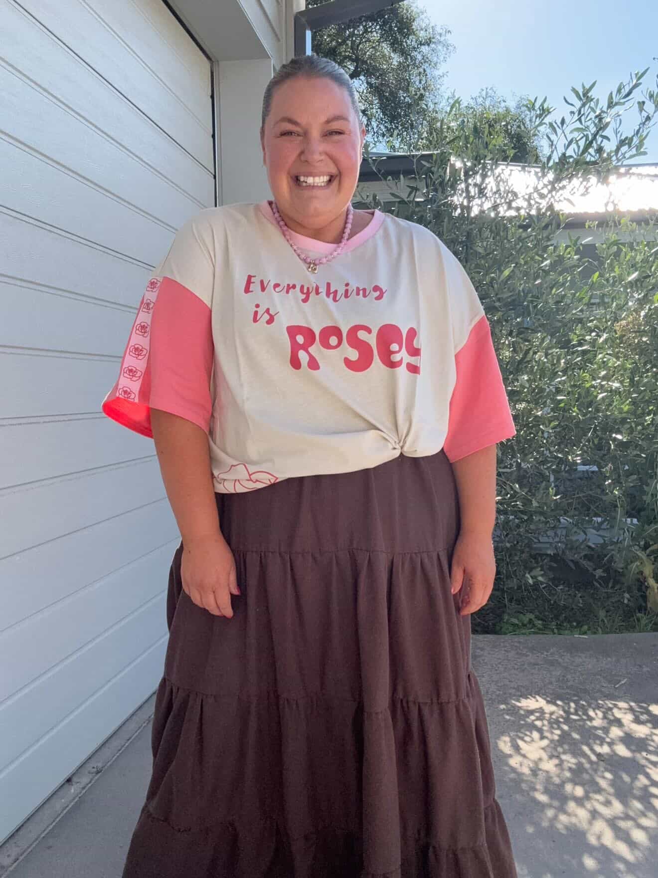 Person wearing a shirt with 'Everything is Roses' text standing outdoors.