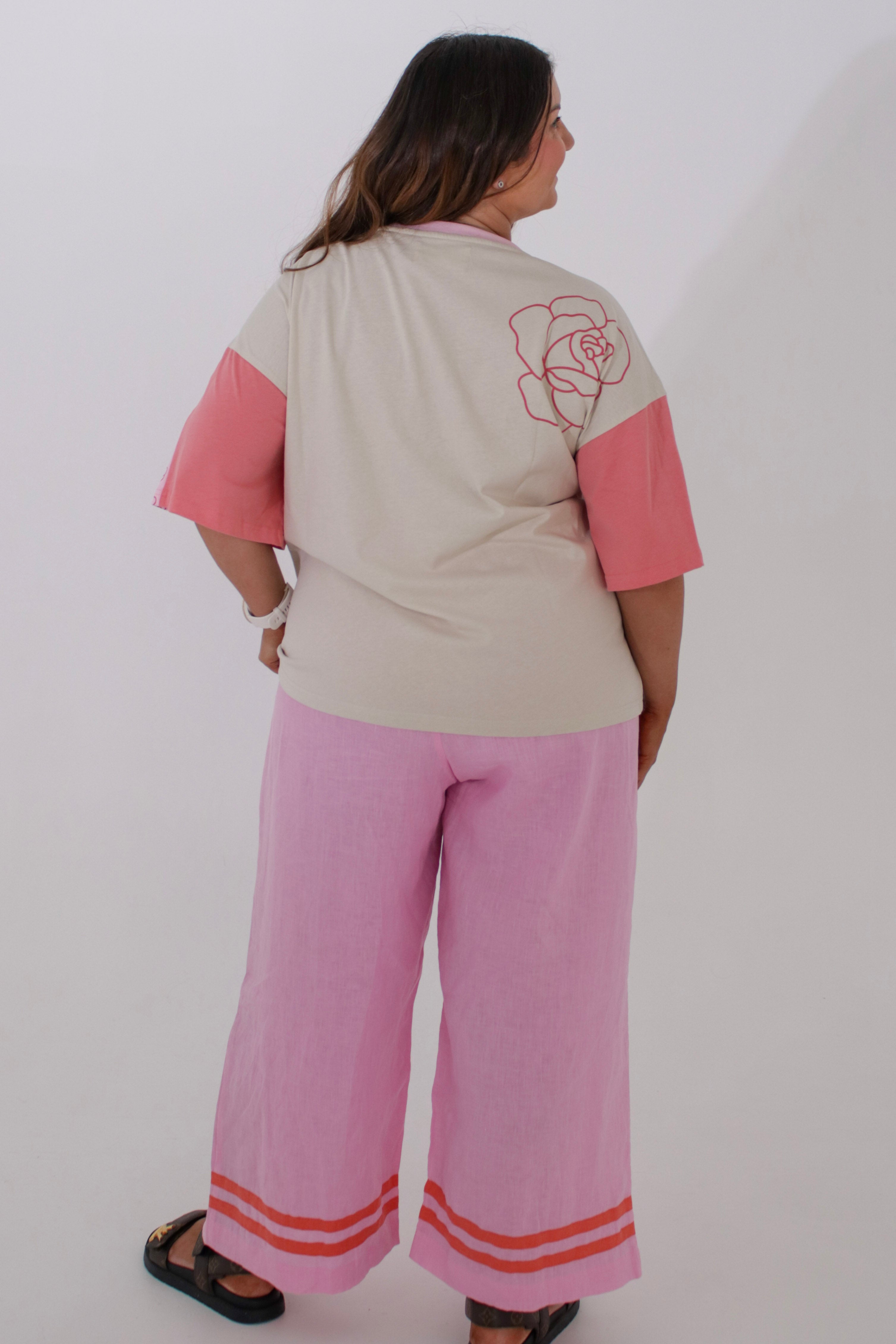 Woman wearing a pink and beige outfit with a rose design on a plain background